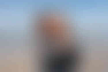 Fiancé kisses smiling woman’s cheek as she shows diamond engagement ring on Cardiff State Beach in San Diego