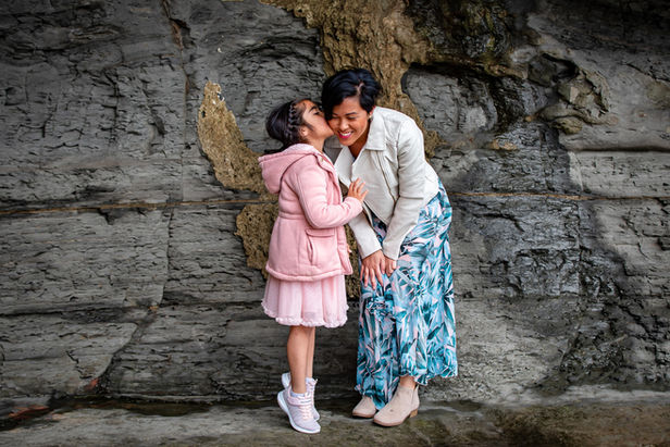 Family photography at Sunset Cliffs in San Diego featuring mother and daughter hugging at sunset