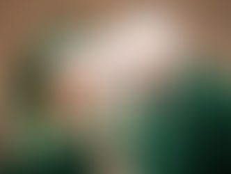 Family wearing green Santa hats and outfits, smiling in a park. The mood is festive and joyful, with brown leaves on the ground.