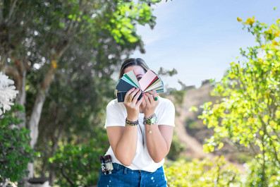 Creative entrepreneur holds paint color swatches outdoors during personal branding photography at Firefly Grove Temecula CA