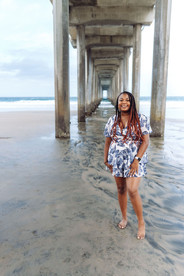 Woman with braids standing barefoot under Scripps Pier for San Diego family photography session