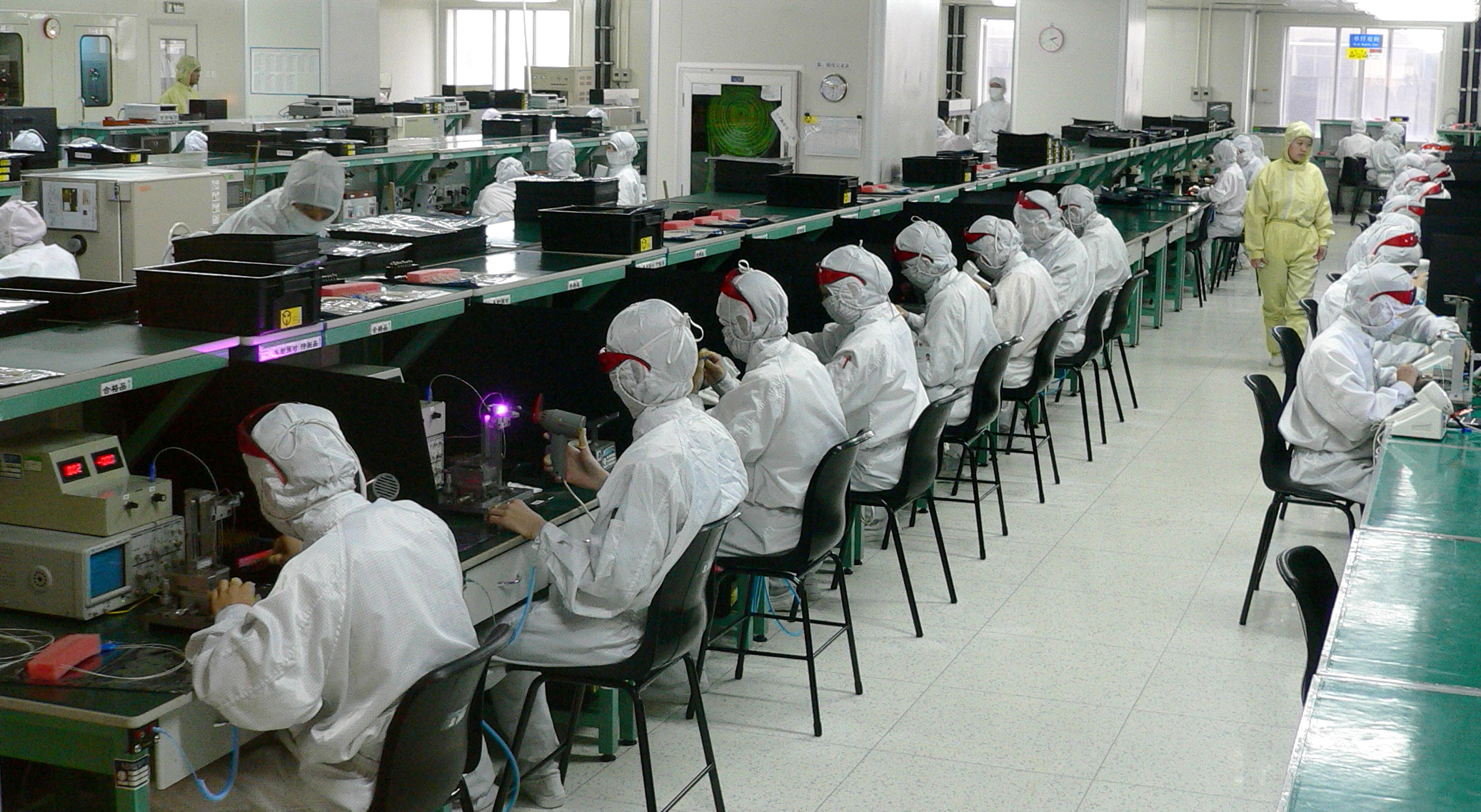 Workers in an electronics component factory in Shenzhen, China, photographed in 2005; archival illustration of manufacturing employment