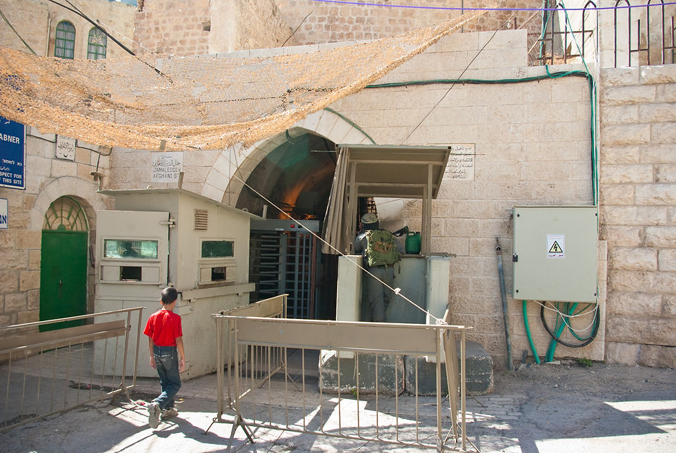 An Israeli military checkpoint in Hebron in September 2009, with a soldier and Palestinian civilians.