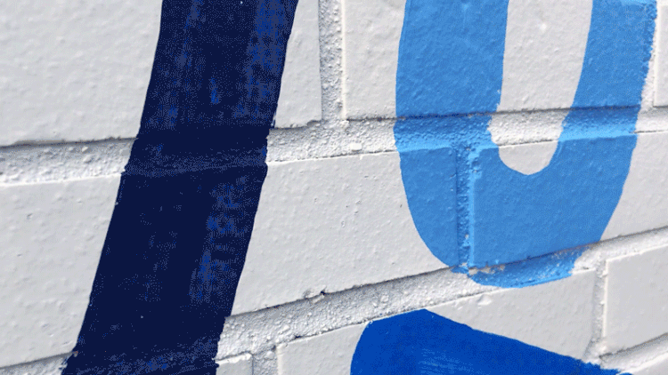 A gif of Adé Hogue painting a typographical mural