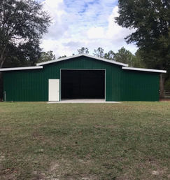 Fully enclosed steel truss pole barn with gable and lean-tos built in Sumter, FL by Patriot Pole Barns, used as a mechanic shop