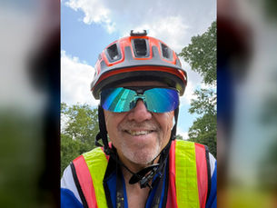 Ken Webster smiling in his cycling helmet and high visibility vest after a 40.97-mile training ride.