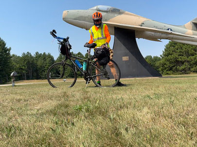 Ken Webster stands with his bicycle beside a military aircraft display outside Escanaba, revisiting a stop from his ride with Don about 20 years ago.