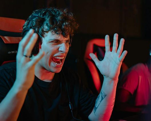 A person in a headset shouts excitedly, raising hands in a gaming chair. Red and blue lighting creates an intense atmosphere.