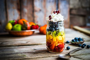 Colorful fruit salad in a jar on rustic wooden background.jpg