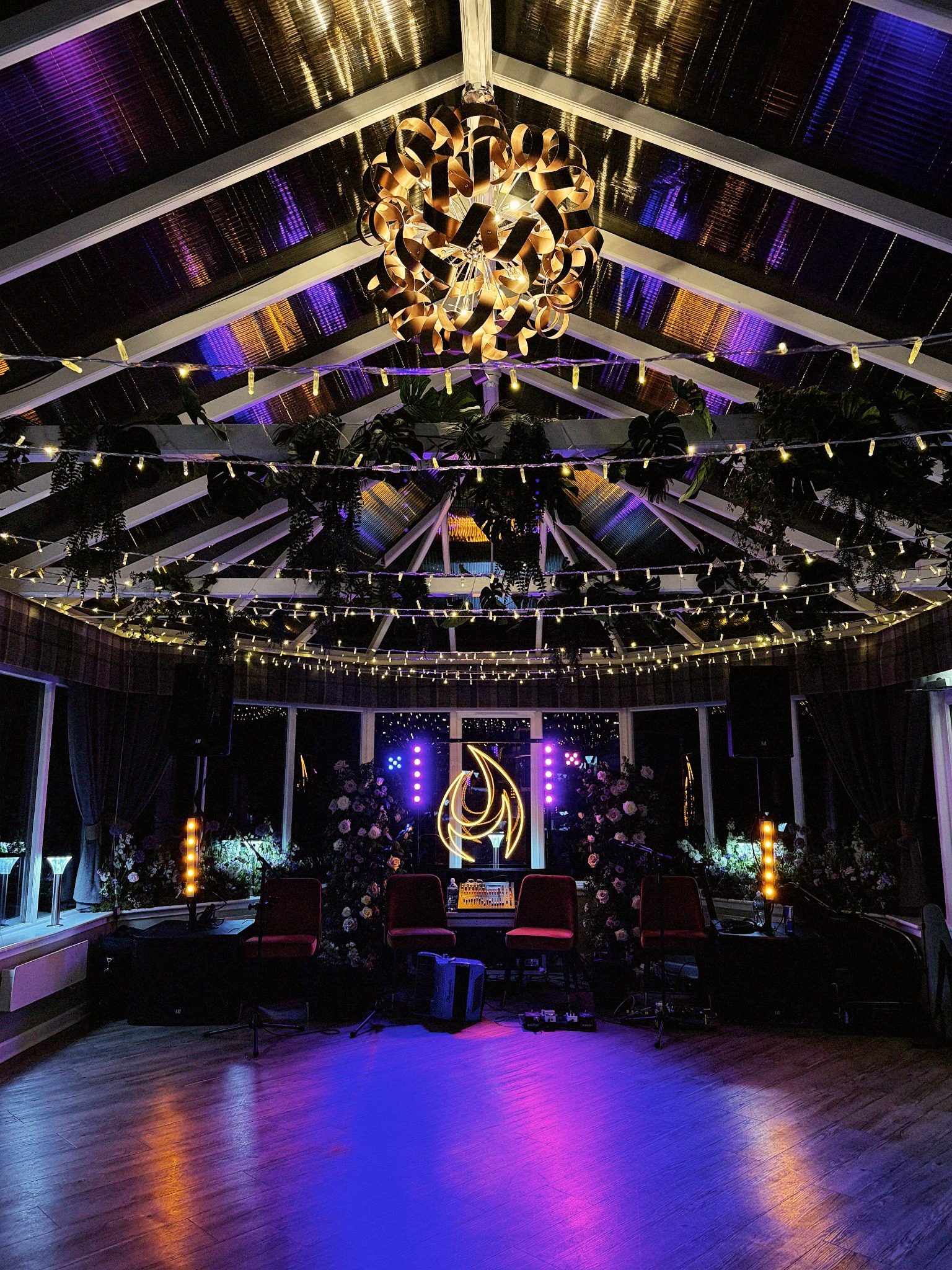Highland Fire stage beneath a chandelier, with purple lighting and a glowing flame sign