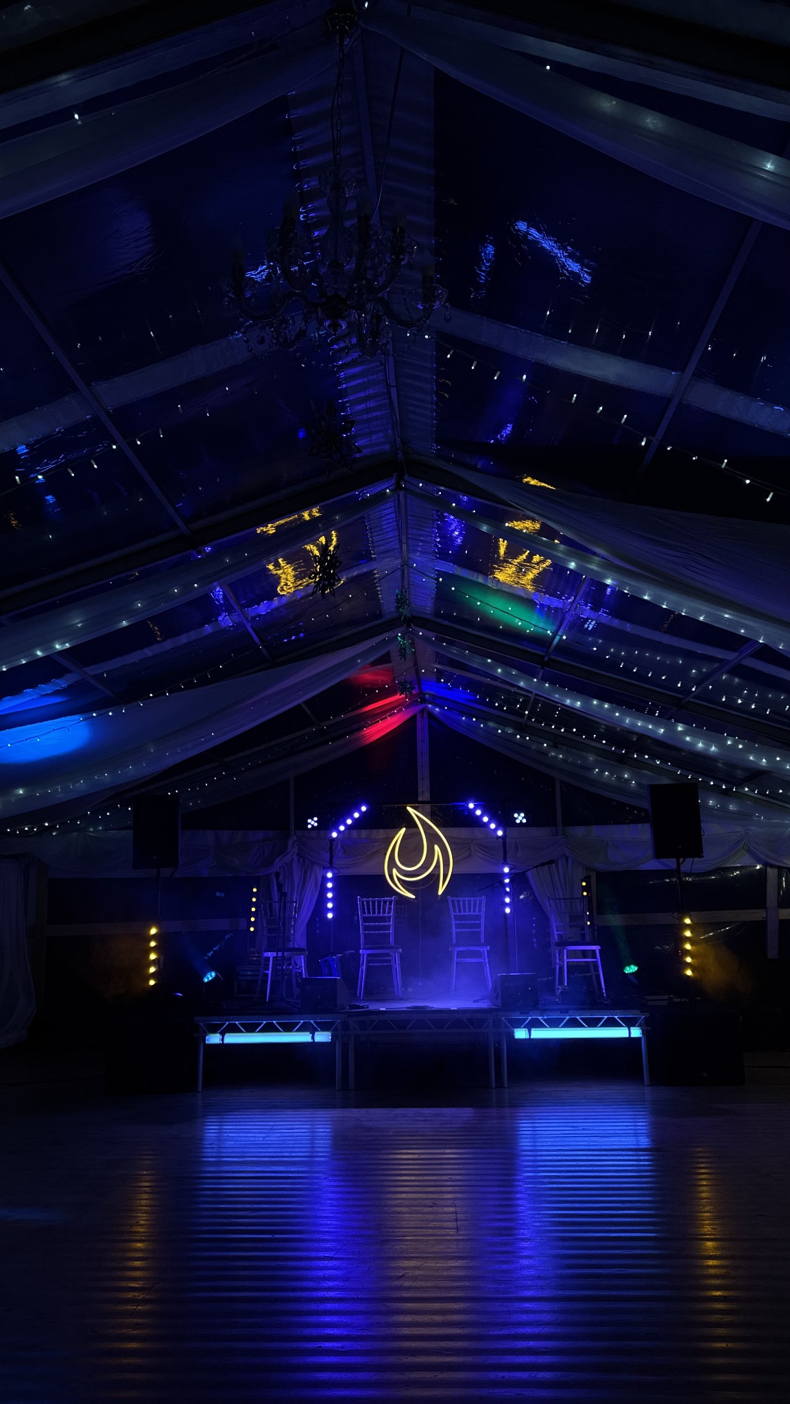 Highland Fire stage and dance floor illuminated in blue inside a marquee