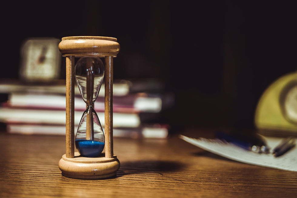 Hourglass with blue sand on a wooden desk, representing the nine-month deadline for director's loan accounts