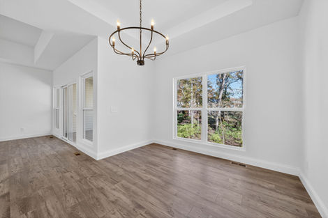Empty room with wood floors, white walls, large windows, and a chandelier