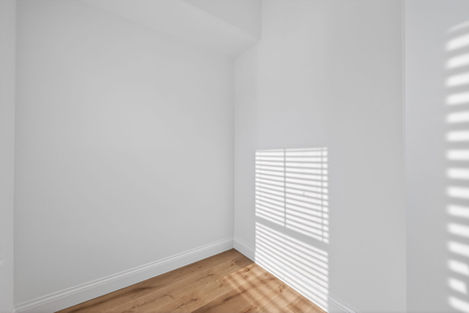 Bright empty room with white walls, wood floor, and window blinds