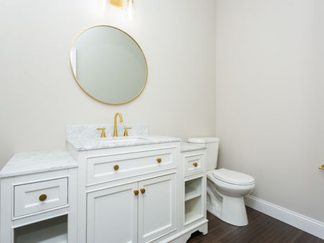 Bathroom with white vanity, gold mirror, and toilet.