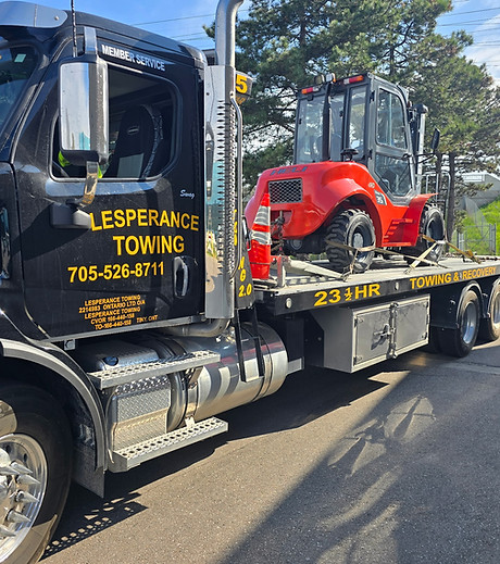 Black towing truck transporting red compact tractor safely