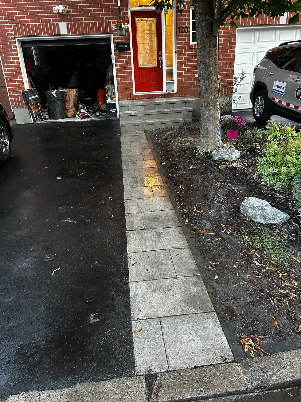 A driveway with a set of steps ascending to a garage, framed by landscaping