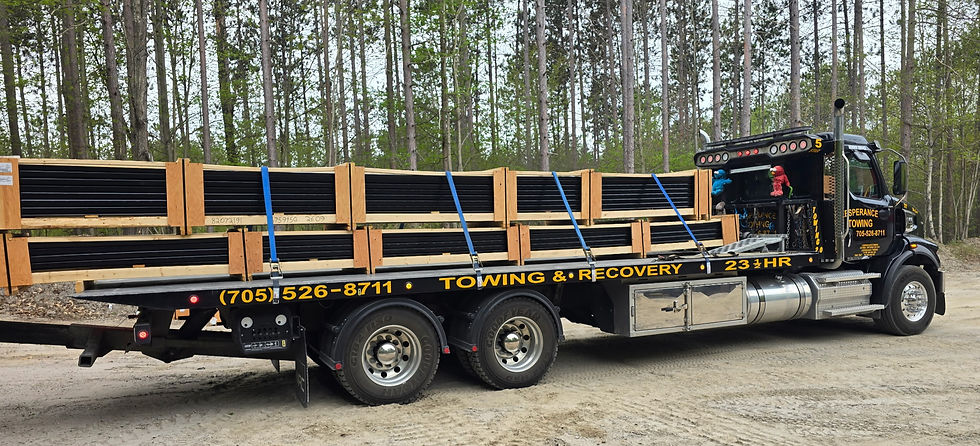 Flatbed tow truck carrying long wooden construction materials