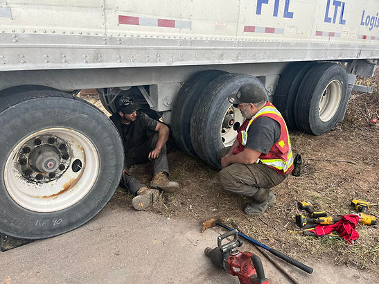 Roadside technician repairing trailer tire and axle