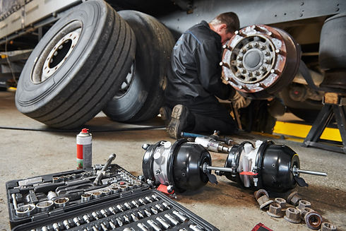 Mechanic works with brakes in truck workshop 