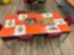 A table with multiple chairs and another table filled with various colorful blocks for play