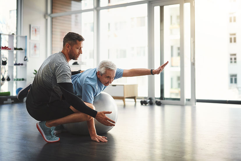 elderly man and physiotherapist with ball for mobility training