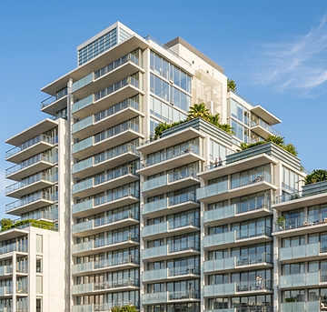 Immeuble de condominiums de luxe moderne en bord de mer, doté de multiples balcons vitrés.