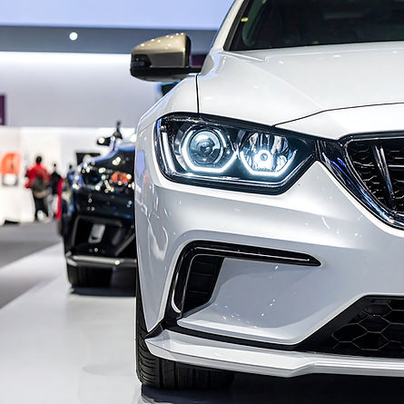 Close-up of a sleek white car's front end with illuminated headlights