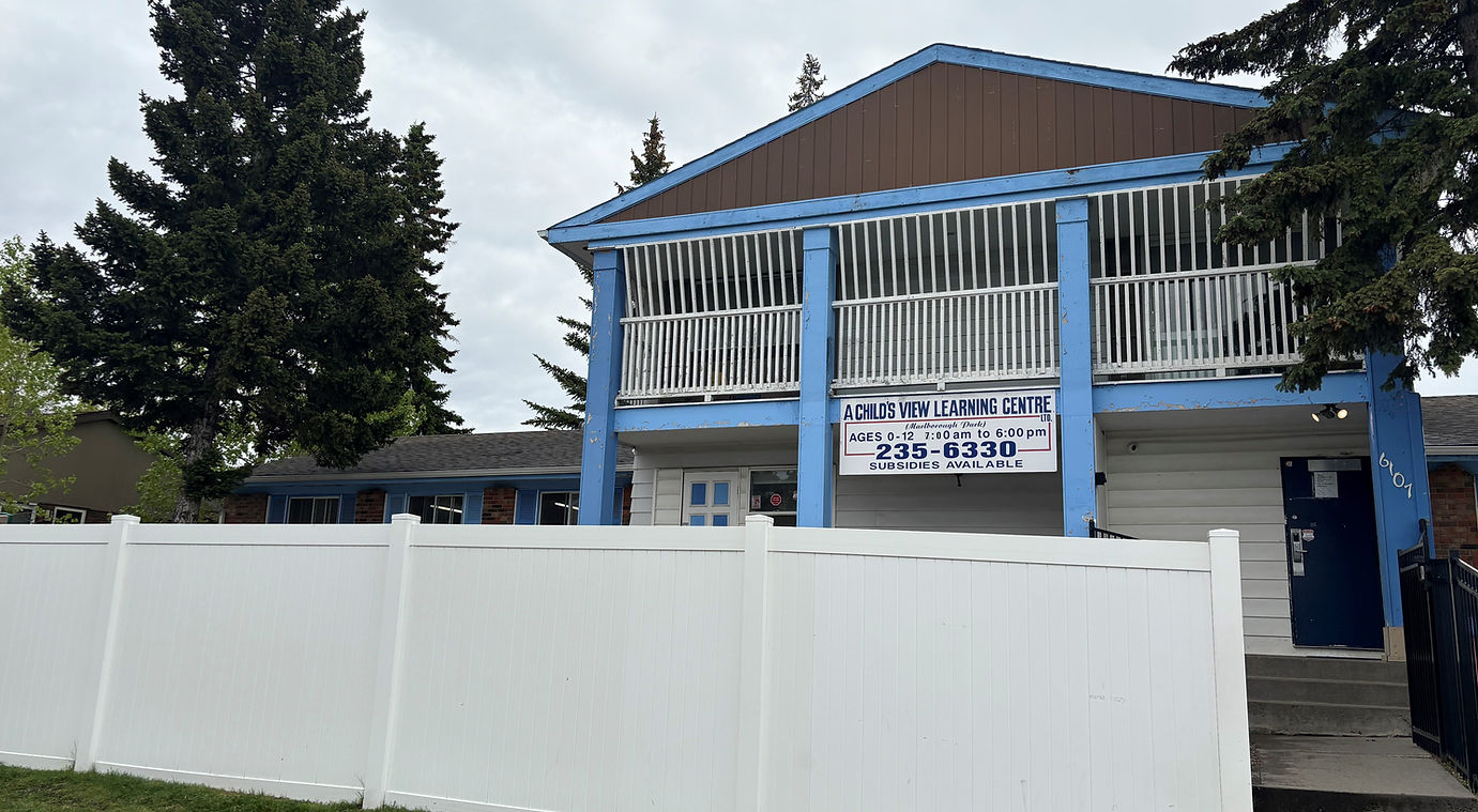 blue and white classroom building surrounded by a white fence