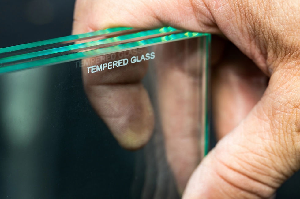 Hand holding toughened glass with inscription that says, “tempered glass.”