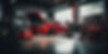 A sleek red sports car with its hood open sits in a dimly lit garage