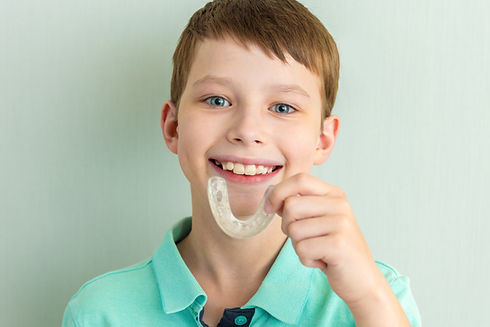 A boy holding a mouthguard in his hand