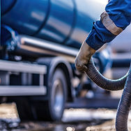Worker connects a suction hose to a sewage tanker truck