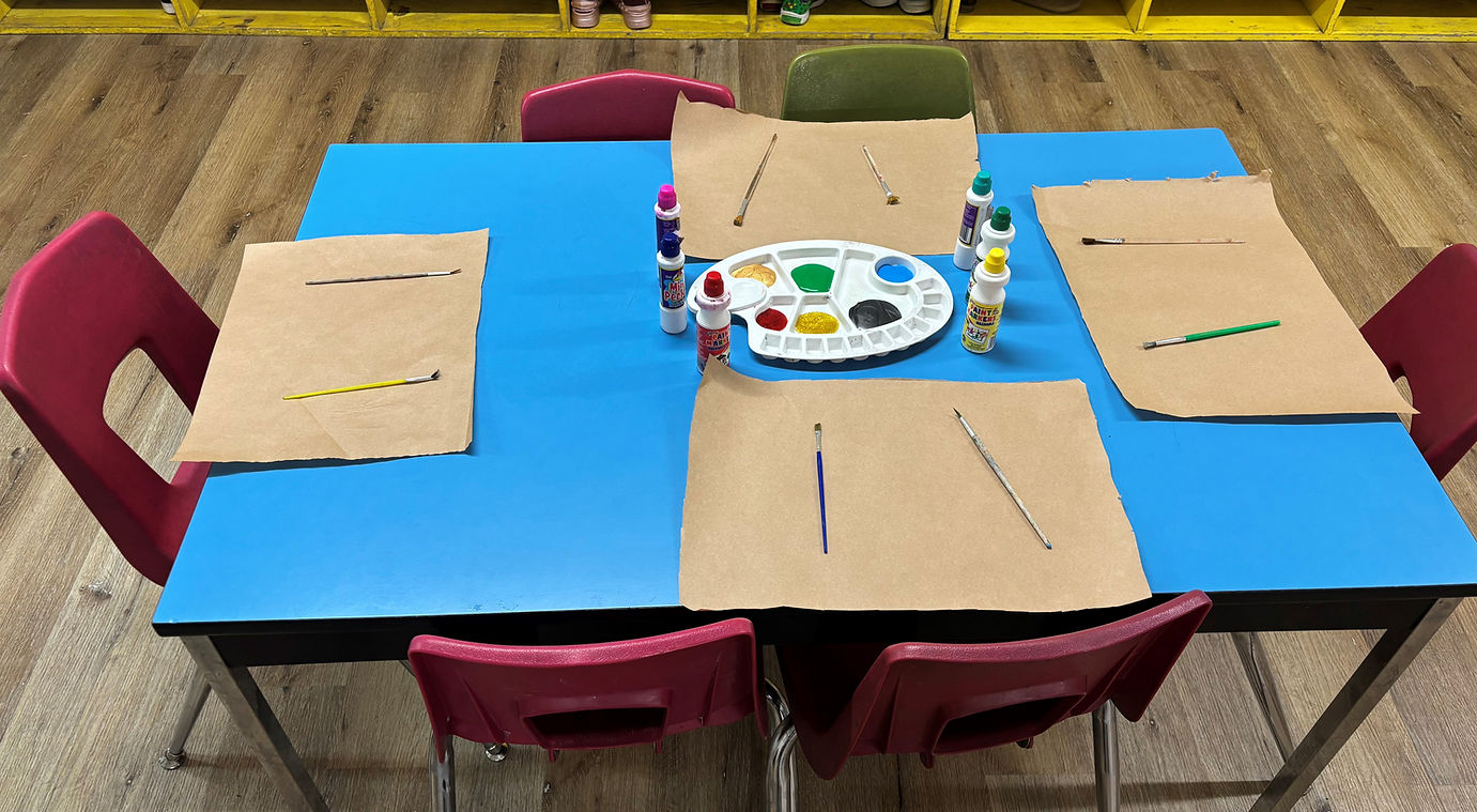 A table set with colorful paint tubes and blank paper for creative artwork