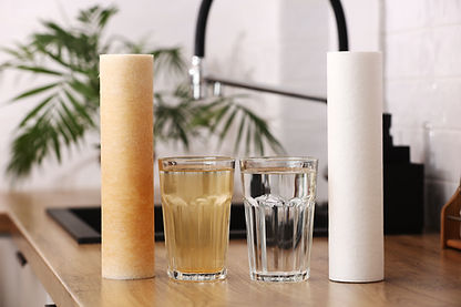 House water filtration system to drinkable condition. New clean water filter cartridge and glass of clear water