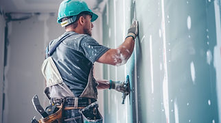 Construction worker in hardhat smoothing plaster on a wall
