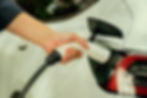 Un homme recharge la batterie d'une voiture électrique