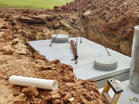 Installation of a large concrete septic tank in a dug-out trench surrounded by soil