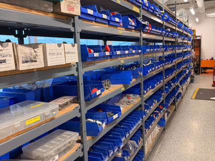 Warehouse shelves stocked with organized automotive parts and blue storage bins