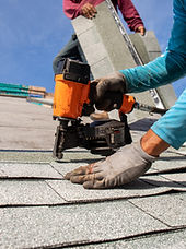 Roofer installing roof shingles with nail gun