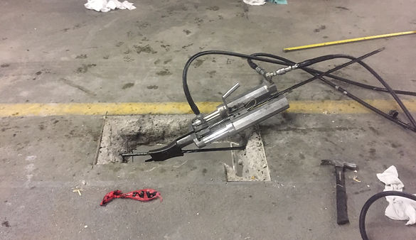 A metal pipe lies on the ground alongside a hose and various tools scattered around it