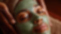 Jeune femme noire profitant d'un masque facial rafraîchissant appliqué par des mains expertes.