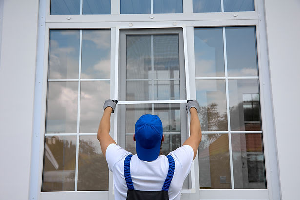 Background of blue-cap worker installing a mosquito net on large plastic window