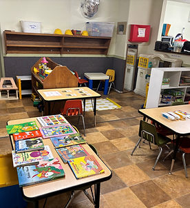 Craft table set up with colorful paints and blank sheets of paper