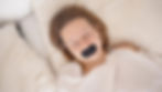 A woman sleeps while wearing a black lip tape