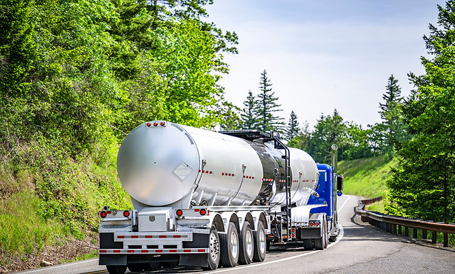 Bright blue big rig semi truck transporting liquid cargo in long tank semi trailer