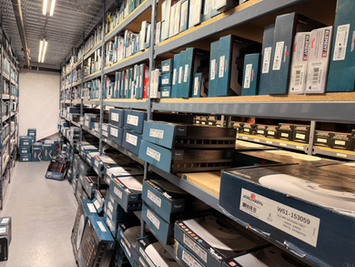 Warehouse aisle featuring organized shelves of boxed automotive replacement parts