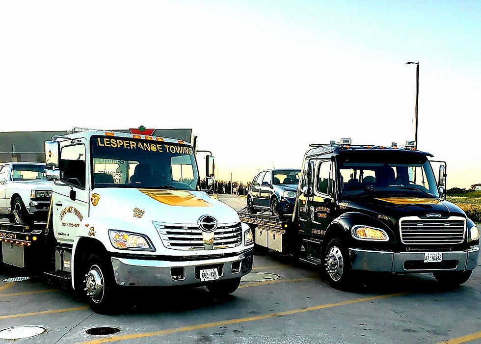 Two towing service trucks parked together in open lot