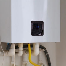 Wall-mounted tankless water heater with digital temperature display and visible plumbing connections