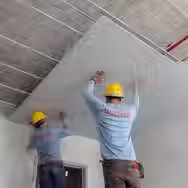 Two person working on the interior roofing of a house